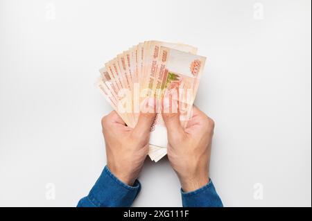 Hände, die fünftausend Dollar Scheine halten. Männliche Hände, die viel Geld auf weißem Hintergrund halten Stockfoto
