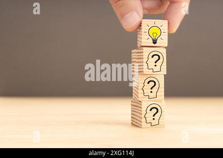 Kreative Idee und Innovationskonzept. Hand Kommissionierung einen Holzblock mit Glühbirne Symbol und menschlichen Kopf mit Fragezeichen innen. Speicherplatz kopieren Stockfoto