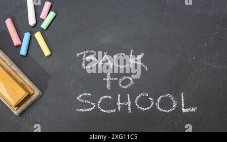 Gruppe von farbigen Kreiden, Radiergummi und handgezeichneter Phrase Back to School auf Tafel Stockfoto