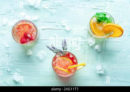 Frische Sommercocktails oder Mocktails, kalte Getränke mit Zitrusfrüchten und Lavendel, Party Limonade, Overhead Flat Lay Shot auf blauem Hintergrund mit Eis Stockfoto