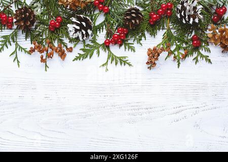 Rand von Weihnachtsbaum Äste Tannenzapfen Blumen und rote Beeren auf weißem Holzhintergrund, kopieren Raum Stockfoto