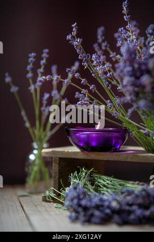 Lila Kerze und Lavendel Blumen Stillleben auf Holz Hintergrund Stockfoto