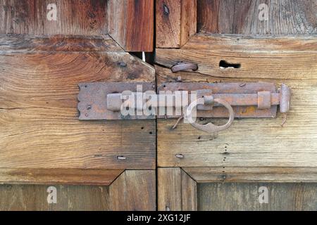 Eine alte antike, rostige Verriegelung an einer Holztür, eine alte, rostige Verriegelung an einer Holztür Stockfoto