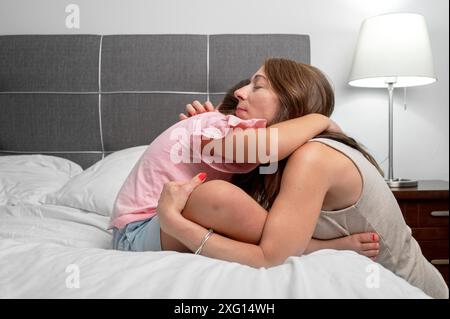 Liebevolle junge Mutter umarmt die verärgerte kleine Tochter, drückt Unterstützung aus, junge Mutter tröstet das liebenswerte kleine Mädchen, zeigt Liebe und Sorgfalt. Stockfoto