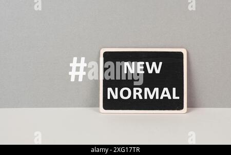 Die Wörter New Normal mit Hashtag stehen auf einem schwarzen, grauen Hintergrund Stockfoto