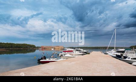 Pier mit Booten in der Bucht an den Festungen von sveti nikola mit dunklen Wolken, sibenik Stockfoto