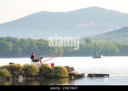 Der junge Mann sitzt und angelt auf dem Kanal sveti ante in sibenik kroatien Stockfoto