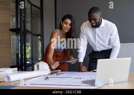 Zusammenarbeit am Projekt, Kollegen, die Blaupausen überprüfen und Tablet im Büro verwenden Stockfoto