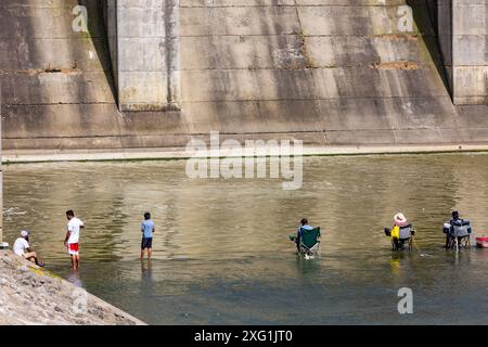 Fischer sitzen im Wasser unter dem Überlauf des J. Edward Roush Dam bei Huntington, Indiana, USA. Stockfoto