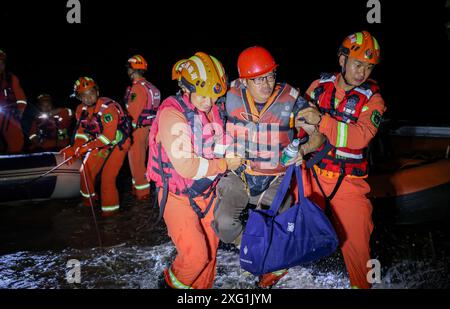 (240706) -- YUEYANG, 6. Juli 2024 (Xinhua) -- Retter bringen einen gestrandeten Bewohner in der Gemeinde Tuanzhou, County Huarong unter der Stadt Yueyang, zentralchinesische Provinz Hunan, 6. Juli 2024. Rettungskräfte, darunter Feuerwehrleute und bewaffnete Polizisten, überwachen genau die Situation eines Deichbruchs im Dongting Lake in der zentralchinesischen Provinz Hunan, der am Freitagnachmittag stattfand, sagten die lokalen Behörden. Die Bresche war ursprünglich etwa 10 Meter breit, hat sich seitdem jedoch weiter ausgebreitet. Die Verlegung von ca. 5.000 Bewohnern des betroffenen Bereichs wurde nach Angaben des örtlichen Unternehmens abgeschlossen Stockfoto