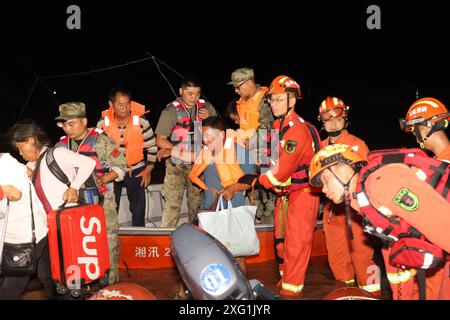 (240706) -- YUEYANG, 6. Juli 2024 (Xinhua) -- Retter verlegen gestrandete Bewohner in der Gemeinde Tuanzhou, County Huarong unter der Stadt Yueyang, zentralchinesische Provinz Hunan, 6. Juli 2024. Rettungskräfte, darunter Feuerwehrleute und bewaffnete Polizisten, überwachen genau die Situation eines Deichbruchs im Dongting Lake in der zentralchinesischen Provinz Hunan, der am Freitagnachmittag stattfand, sagten die lokalen Behörden. Die Bresche war ursprünglich etwa 10 Meter breit, hat sich seitdem jedoch weiter ausgebreitet. Nach Angaben des örtlichen flo wurde die Verlegung von ca. 5.000 Bewohnern des betroffenen Bereichs abgeschlossen Stockfoto