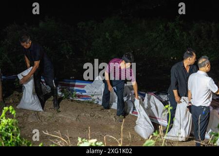 (240706) -- YUEYANG, 6. Juli 2024 (Xinhua) -- Retter verstärken einen Deich in der Gemeinde Tuanzhou, County Huarong unter der Stadt Yueyang, zentralchinesische Provinz Hunan, 6. Juli 2024. Rettungskräfte, darunter Feuerwehrleute und bewaffnete Polizisten, überwachen genau die Situation eines Deichbruchs im Dongting Lake in der zentralchinesischen Provinz Hunan, der am Freitagnachmittag stattfand, sagten die lokalen Behörden. Die Bresche war ursprünglich etwa 10 Meter breit, hat sich seitdem jedoch weiter ausgebreitet. Die Verlegung von ca. 5.000 Bewohnern des betroffenen Bereichs wurde nach Auskunft des örtlichen Hochwasserschutzes abgeschlossen Stockfoto