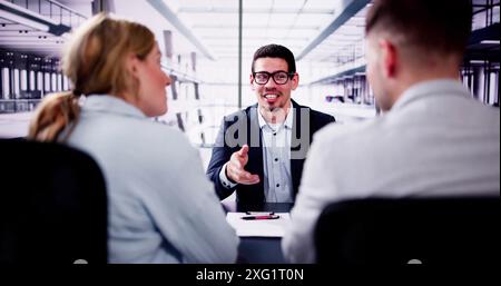 Der Finanzberater berät sich mit dem jungen Paar über zukünftige Investitionen in sein Büro, wobei er ein Notebook und das Notebook des Kunden als Referenz verwendet Stockfoto