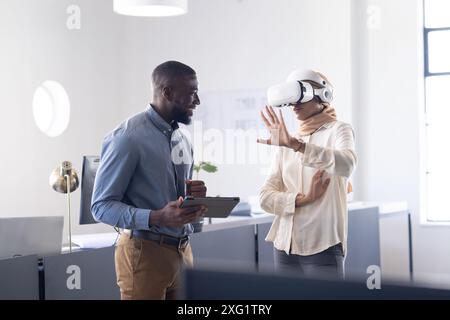 Mit VR-Headset, Frau, die mit virtueller Umgebung interagiert, Kollegen beobachten Stockfoto