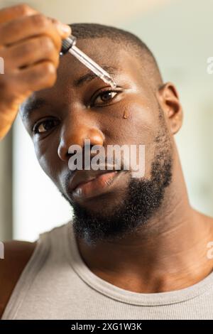 Gesichtsserum auftragen, Mann mit Fokus auf Hautpflegeroutine zu Hause Stockfoto