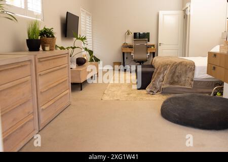 Modernes Schlafzimmer mit Schreibtisch, Computer und Pflanzen, gemütlicher Arbeitsbereich und Kopierbereich Stockfoto