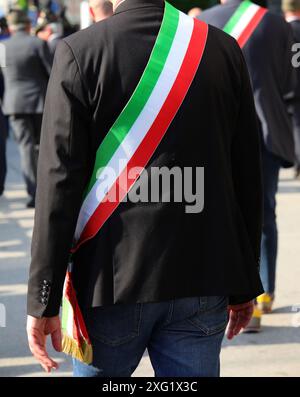 Italienischer Bürgermeister in einer schwarzen Jacke und dem dreifarbigen Schärpe der italienischen Flagge während der Parade durch die Straßen der Stadt Stockfoto