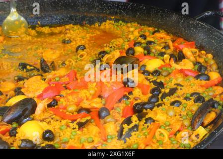 Detail der Zutaten der valencianischen Fischpaella mit Reis roten Paprika Reis grüne Erbsen Oliven Muscheln Weichtiere und Tomaten Stockfoto