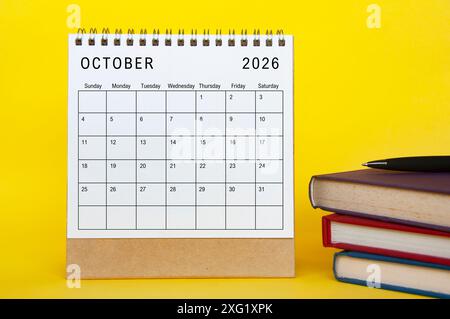 Oktober 2026 Kalender mit gelbem Umschlaghintergrund und Büchern. Neues Monatskonzept und Kalenderkonzept Stockfoto