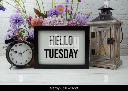 Hello Tuesday Text mit Blumen, Holzlaterne und Wecker Dekoration Stockfoto
