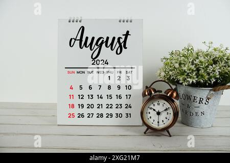 Monatskalender August 2024 mit Vintage-Wecker auf hölzernem Hintergrund Stockfoto