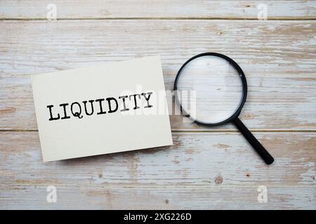 Liquiditäts-Textnachricht und Lupe mit Raumkopie auf hölzernem Hintergrund Stockfoto