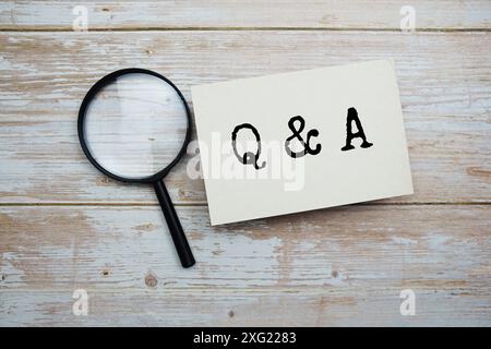 Frage- und Antwortnachricht und Lupe mit Raumkopie auf hölzernem Hintergrund Stockfoto