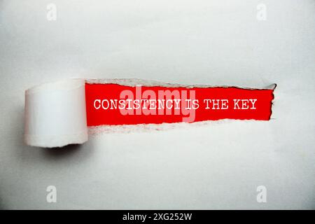 Konsistenz ist die Schlüsselbotschaft auf rotem Papier mit gerissenem Hintergrund Stockfoto