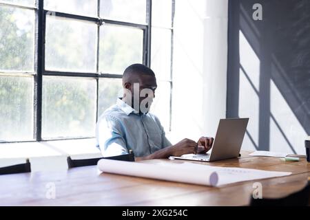 Arbeiten am Laptop, Mann sitzt am Schreibtisch in heller Büroumgebung Stockfoto