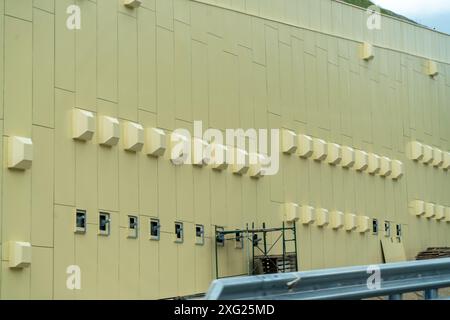 Ein großes Gebäude mit vielen Fenstern und Lüftungsschlitzen. Das Gebäude ist gelb und hat viele Fenster. Stockfoto