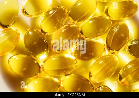 Schüssel gefüllt mit gelbem Fischöl, reich an Omega-3-Fettsäuren. Die Tabletten sind oval und gelb. Sie sind in einem Stapel auf einem weißen s angeordnet Stockfoto