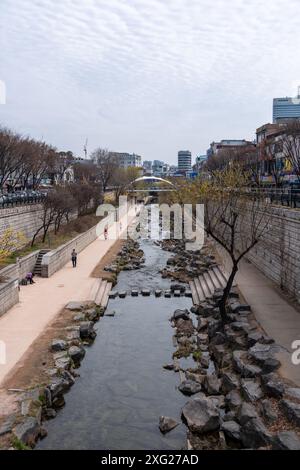 Seoul, Südkorea - 24. März 2024: Menschen, die am Cheonggyecheon-Fluss, einem modernen öffentlichen Raum in Seoul, Südkorea, zu Beginn des Frühlings spazieren. Stockfoto