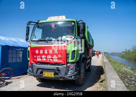 Hunan, China. Juli 2024. (240706) -- YUEYANG, 6. Juli 2024 (Xinhua) -- Ein mit Sand und Steinen beladener Lastwagen fährt zum Ort eines Deichbruchs in der Gemeinde Tuanzhou, County Huarong unter der Stadt Yueyang, zentralchinesische Provinz Hunan, 6. Juli 2024. Nach Angaben des Ministeriums für Notfallmanagement wurde ein Arbeitsteam in die zentralchinesische Provinz Hunan entsandt, um Rettungsmaßnahmen nach einem Deichbruch im zweitgrößten Süßwassersee des Landes am Freitagnachmittag zu leiten. Mehr als 800 Personen des China National Comprehensive Fire and Rescue Teams, 146 Fahrzeuge und 82 Boote waren dabei Stockfoto