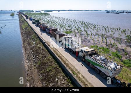 Hunan, China. Juli 2024. (240706) -- YUEYANG, 6. Juli 2024 (Xinhua) -- Ein Drohnenfoto vom 6. Juli 2024 zeigt Lkw mit Steinen in der Schlange in der Gemeinde Tuanzhou, County Huarong unter Yueyang, zentralchinesischer Provinz Hunan. Nach Angaben des Ministeriums für Notfallmanagement wurde ein Arbeitsteam in die zentralchinesische Provinz Hunan entsandt, um Rettungsmaßnahmen nach einem Deichbruch im zweitgrößten Süßwassersee des Landes am Freitagnachmittag zu leiten. Mehr als 800 Menschen vom chinesischen nationalen Feuerwehrteam, 146 Fahrzeuge und 82 Boote wurden gesungen Stockfoto