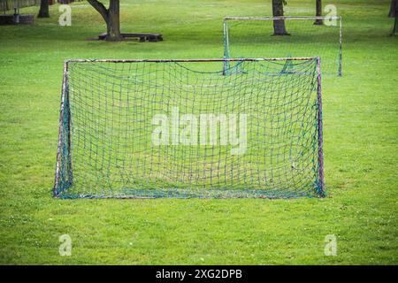 Alte einfache Fußballtore mit rostigen Metallrahmen und geflickten Netzen auf der Wiese in einem Park, oft von der Dorfjugend genutzt, Kopierraum, ausgewählter Fokus Stockfoto