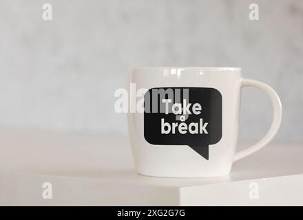 Die Nachricht Take a Break auf einer Sprechblase, die auf einer Kaffeetasse über dem Tisch gedruckt ist. Geschäftskonzept für Pause und Pause am Arbeitsplatz. Stockfoto