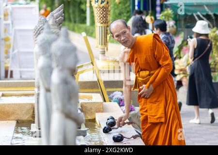 BANGKOK, THAILAND, 16. JUNI 2024, Ein buddhistischer Mönch steht an einer Statue in einem buddhistischen Tempel Stockfoto