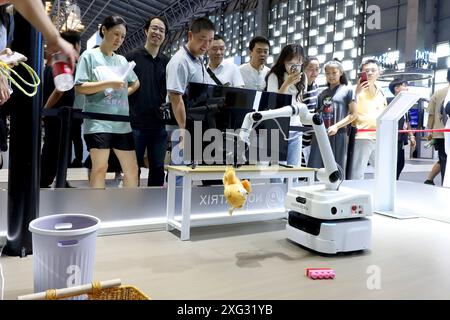 Shanghai, China. Juli 2024. Besucher beobachten während der World AI Conference 2024 in Shanghai, Ostchina, am 6. Juli 2024 einen Heimroboter, der während der Arbeit arbeitet. KI-basierte Produkte und Anwendungen haben viele Besucher während der World AI Conference 2024 in ihren Bann gezogen. Quelle: Fang Zhe/Xinhua/Alamy Live News Stockfoto