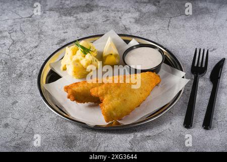 Frittiertes, beschichtetes Fischfilet mit Kartoffelsalat auf Steintisch Stockfoto