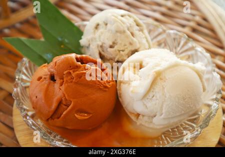 Nahaufnahme von drei Schaufeln gesüßtem Thai-Tee und Kokosnussmilch-Eis in einer Glasschale Stockfoto