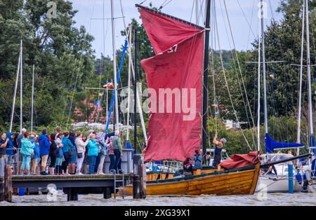 Wustrow, Deutschland. Juli 2024. Die Segel eines Zeesboots, ein bis zu 12 Meter langes, formstabiles Schwertboot aus den Tagen des Segelfischens mit den typischen braunen Segeln, werden zu Beginn der 38. Wustrow Zeesboot Regatta gesetzt, die den Hafen verlässt. Am Saaler Bodden zwischen Festland und Fischland-Darss-Zingt findet die Regatta in drei Bootsklassen bei starkem Wind und Schwung statt. Quelle: Jens Büttner/dpa/Alamy Live News Stockfoto