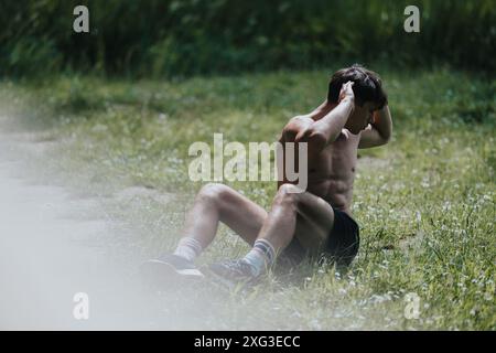 Fitter Mann, der während des Trainings im Park Sit-UPS macht Stockfoto
