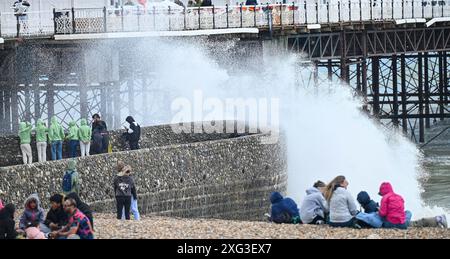 Brighton UK 6. Juli 2024 - die Besucher werden nass, wenn die Wellen an einem windigen, stürmischen Tag entlang der Südküste von Brighton über Brighton krachen: Credit Simon Dack / Alamy Live News Stockfoto