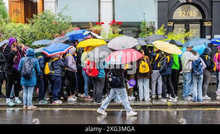 London, Großbritannien. Juli 2024. Die Menschen unterbringen sich unter Sonnenschirmen, während sie bei nassem, kaltem und windigem Wetter vor dem britischen Museum anstehen. Guy Bell/Alamy Live News Stockfoto