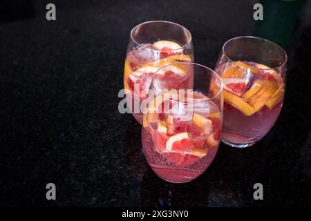 Drei Gläser gefüllt mit Grapefruit und Gin Tonic, vor schwarzem Hintergrund Stockfoto