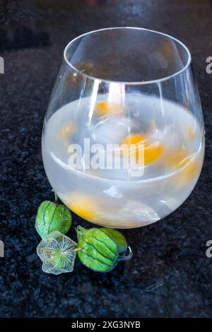 Swirling Gin und Tonic mit leuchtend orangen Stachelbeeren. Stockfoto