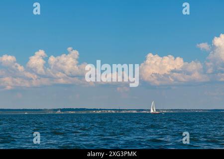 Yacht, weißes Segelboot unter Kopf genua und Hauptsegel segeln in einem ruhigen Meer in der Nähe der Küste. Kreuzfahrt, Urlaub, Regatta, Sport. Golf von Finnland. Banne Stockfoto