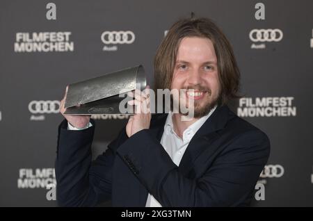 München, Deutschland. Juli 2024. Produzent Christian Jilka überreicht seinen Preis nach der Zeremonie im Amerika-Haus während der Münchner Filmfestspiele. Unter anderem werden internationale Filmemacher und Nachwuchstalente geehrt. Zuschauerpreise werden ebenfalls vergeben. Quelle: Felix Hörhager/dpa/Alamy Live News Stockfoto