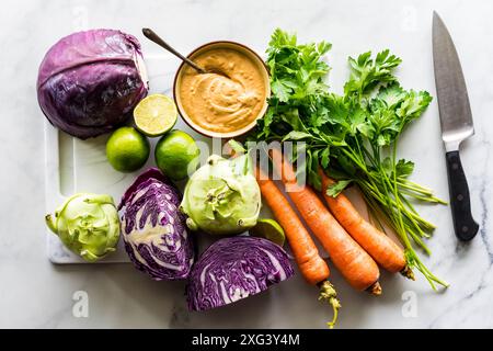 Frisches Gemüse auf einem Schneidebrett mit Erdnusssoße, um einen Kohlsalat zu machen. Stockfoto