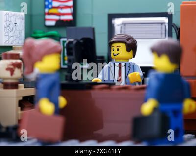 Tambow, Russische Föderation - 2. Juli 2024 Eine Minifigur eines Lego-Geschäftsmannes, die hinter einem Computer arbeitet, während zwei andere Geschäftsleute ein Gespräch führen Stockfoto